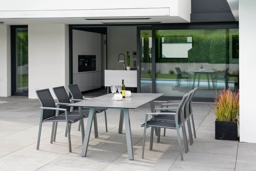 6 Aluminium Stühle an einem individuell zusammengestellten Tisch von Stern auf einer Steinterrasse vor einem Haus
